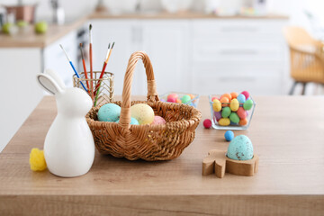 Basket with Easter eggs and figure of bunny on table in kitchen