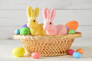 Basket with cute Easter bunnies and eggs on light background