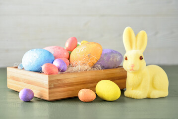 Wooden box with eggs and cute Easter bunny on table