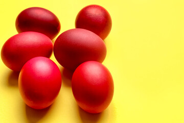 Red Easter eggs on yellow background, closeup