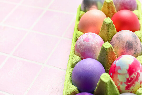 Holder with beautiful Easter eggs on color tile, closeup