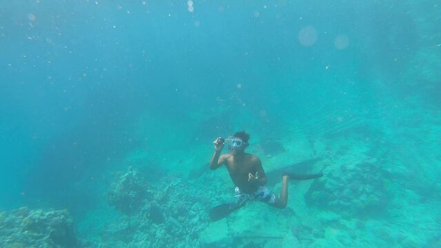 Scuba diver with camera take photos of romantic couple on water surface at snorking on excursions to the islands