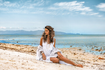 Fototapeta na wymiar Beautiful young stylish woman in white dress on the beach