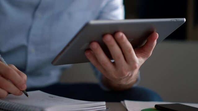 Entrepreneur man using tablet writing notebook information research in workplace
