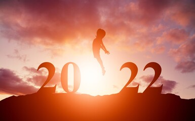 Young traveler jumping at beautiful sunset celebrating New Year 2022, Summer vacation concept