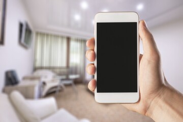 Human using smartphone, controlling smart home systems in modern apartment, blank screen