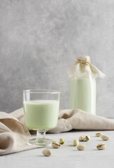 Pistachio milk the glass next to bottle of milk and pistachios