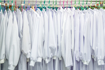 white medical uniform clothes on hangers in store or in hospital