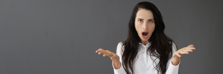 Young surprised woman portrait on gray background