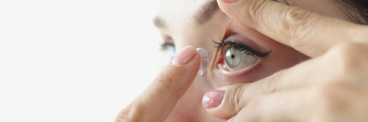 Young woman inserting contact lens into her eye closeup