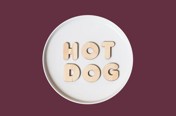 The word Hot dog made of wooden letters on a round white plate