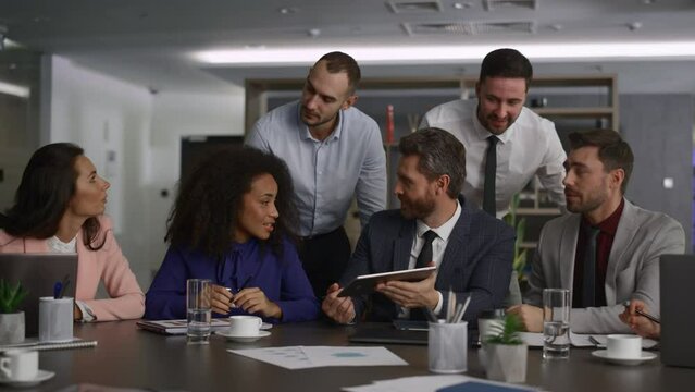 Business group researching tablet device in diverse international office company