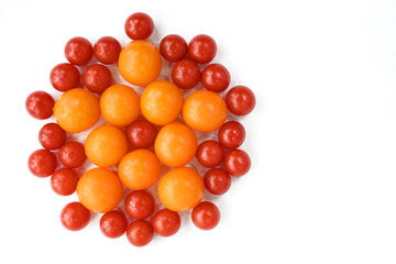 Red and yellow tomatoes stacked on a white table in the form of a flower. Flat lay, top view, close up, macro