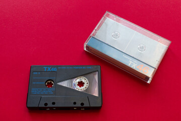 Vintage audio cassette tape and cassette tape case on red background. Technology from the 90s.