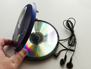 Hand opening a vintage CD Walkman with headphones on white background. Vintage Technology from the...