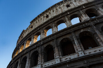The sun sets on the Colosseum in Rome, Italy, the largest ancient amphitheatre ever built, during a cloudless summer day.