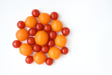 Red and yellow tomatoes stacked on a white table in the form of a flower