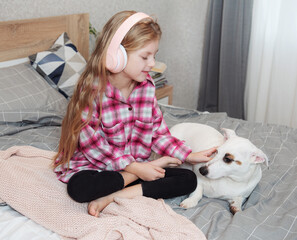 Girl and dog sitting on couch in headphones
