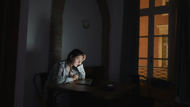 Woman staring at laptop screen at night wearing pajama