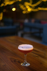 Pink tasty cocktail with foam in mister glass on the wooden table. Close up photo, bar. High quality photo