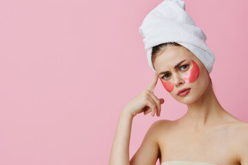 woman pink patches on the face with a towel on the head pink background