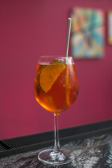 Aperol spritz summer cocktail in mister glass with lime, eco friendly straw and bubbles. Close up. Pink background. High quality photo