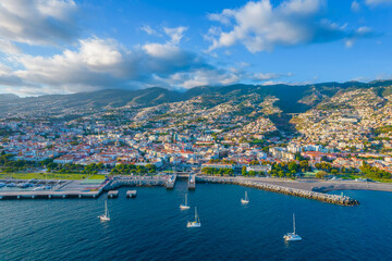 Fototapeta na wymiar Aerial drone view of Funchal city center and port panorama in Madeira island in the evening. It's Portugal's Autonomous Region and is located in Atlantic ocean