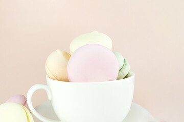 Delicious Sweet Colorful marshmallows looks like Macarons in porcelain white coffee cup mug, colorful almond cookies, pastel colors.