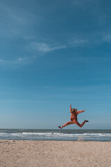 Fototapeta na wymiar woman jumping happy in the beach with a blue sky and sea in the background