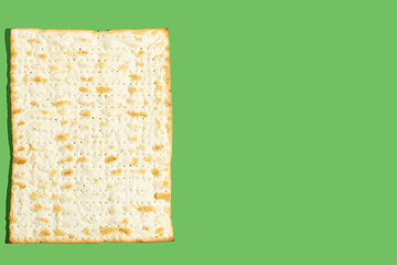Matzah bread for Jewish holiday Pesach on green background with copy space.