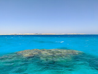 Beautiful view of the azure red sea and coral reef against the blue sky. Copy space. Hurghada, Egypt.