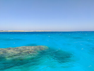 Beautiful view of the azure red sea and coral reef against the blue sky. Copy space. Hurghada, Egypt.