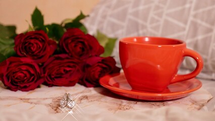 Background Festive Flatlay, composition for Valentine's Day on February 14. Coffee in a red cup, red rose flowers and diamond heart earrings at home in bed