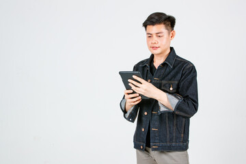 Portrait studio shot Asian young confident handsome cool short hair male hipster model wearing casual street denim jeans jacket standing holding tablet computer pointing at camera on gray background