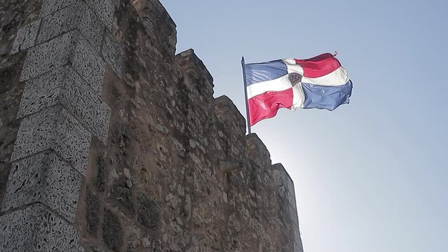 bandera de la rep&uacute;blica dominicana ondeando en lo alto de la fortaleza de ozama en la zona colonial.