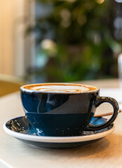 Coffee in a blue cup on a wooden table in cafe or coffee shop. Morning. Lifestyle. Blurred background.