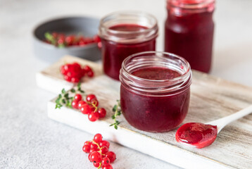 Homemade red currant jam or jelly in glass jars and red currants berries.