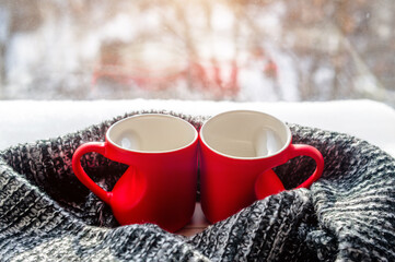 Fototapeta na wymiar two heart shaped mugs with tea on the background of a window in winter 