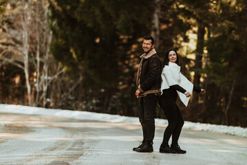 Loving couple standing back to back in winter on the background of a snowy highway. Selective focus.