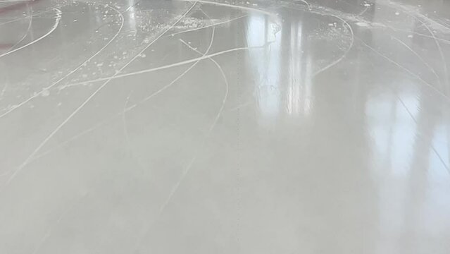 Traces of ice skates on the ice rink. Ice background with marks from skating. Traces of hockey skates in slow motion. Ice rink floor, detailed.