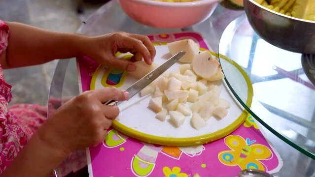 Woman cuts apple into small pieces preparing ingredients for baking fruit pie
