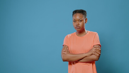 Serious person feeling furious and standing with arms crossed in studio. Annoyed woman looking at camera with angry facial expression. Aggressive adult having bad attitude problem