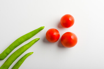 Fresh Green chilli and tomatos on white background.