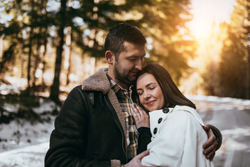 Happy couple hugginng and smiling outdoors in snowy park. Selective focus.