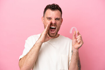 Brazilian man holding invisible braces shouting with mouth wide open