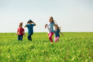 A group of happy children of boys and girls run in the Park on the grass on a Sunny summer day . The concept of ethnic friendship, peace, kindness, childhood