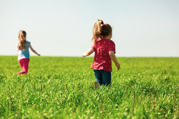 A group of happy children of boys and girls run in the Park on the grass on a Sunny summer day . The concept of ethnic friendship, peace, kindness, childhood