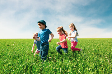 A group of happy children of boys and girls run in the Park on the grass on a Sunny summer day . The concept of ethnic friendship, peace, kindness, childhood