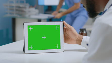 African american specialist doctor looking at mock up green screen chroma key tablet computer with isolated display. Physician man working at medical expertise in hospital office. Medicine services - Powered by Adobe
