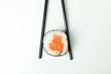 Chopsticks with maki on white background, close up